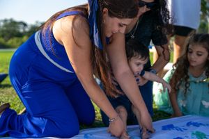 Group activity showing multiple people creating colorful handprints on white fabric.