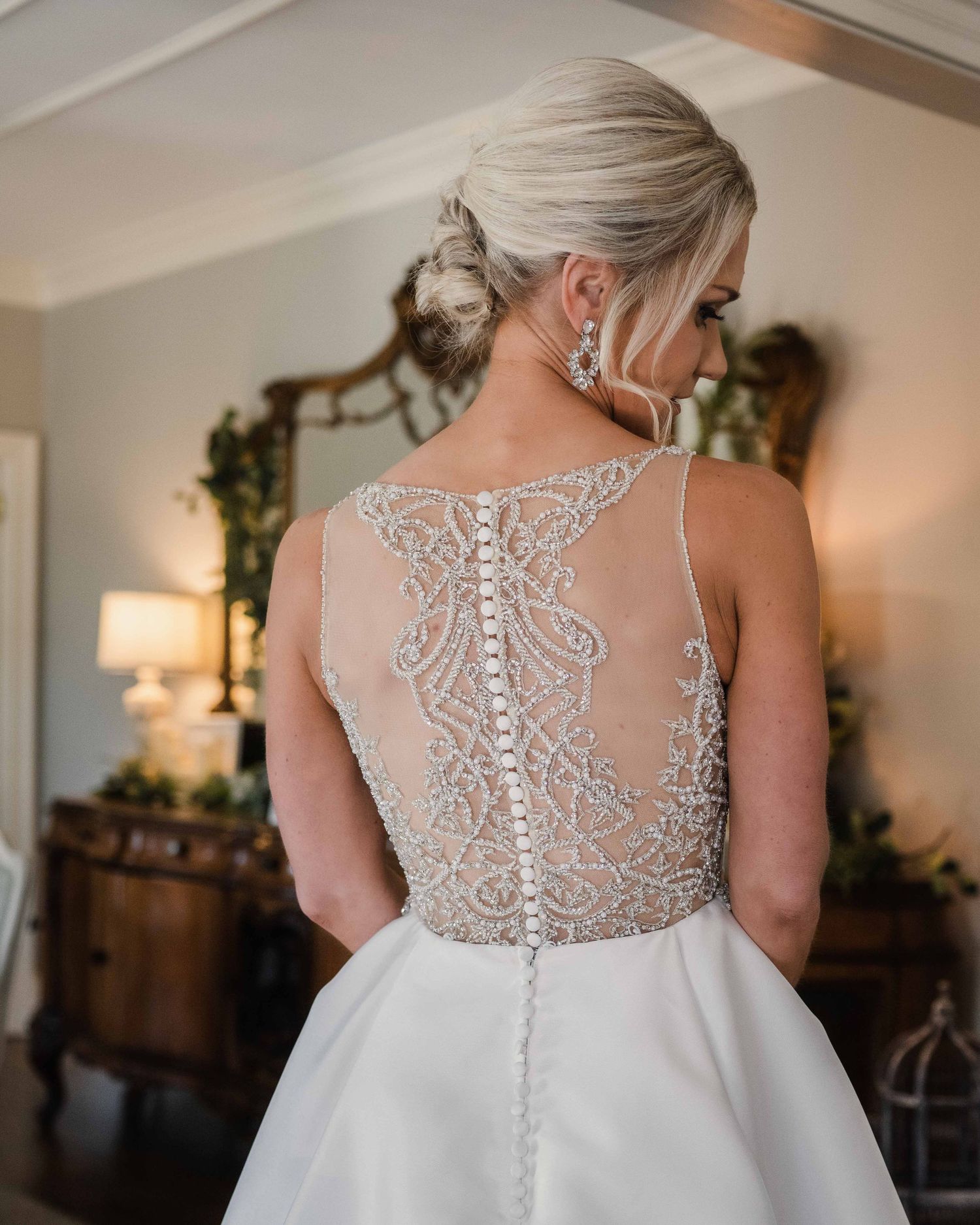 Close-up of intricate beaded lace detail on back of white wedding gown.