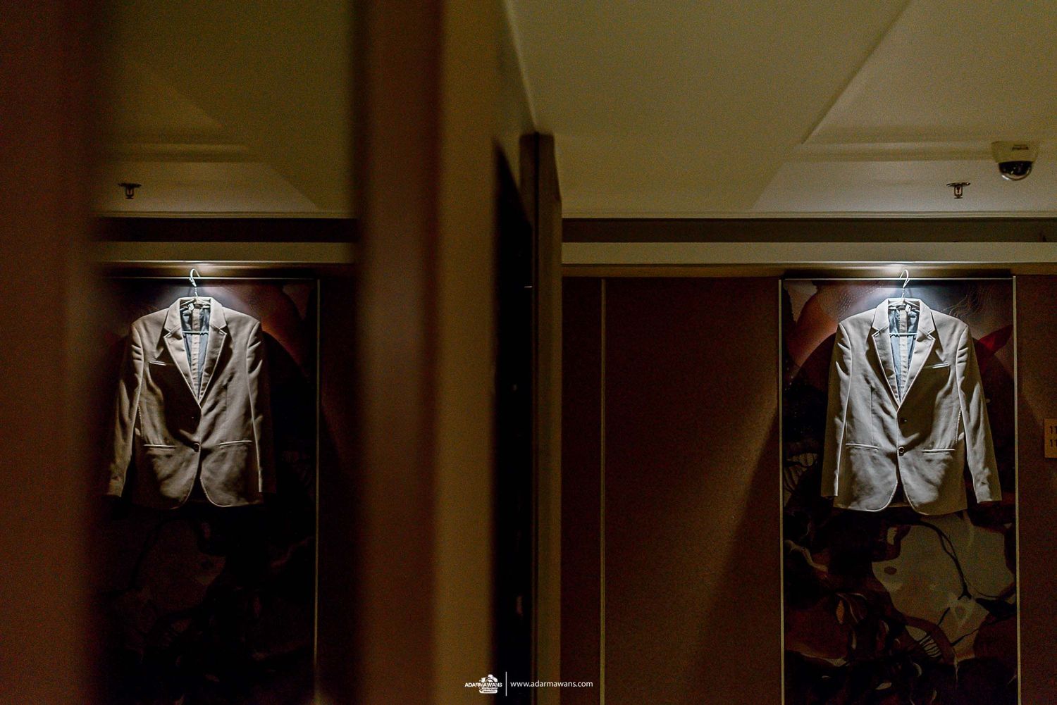 Elegant grey suit jacket displayed in mirrored wardrobe with dramatic lighting.