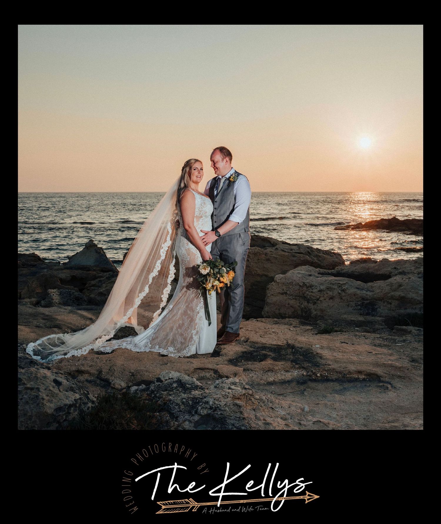 Sunset beach wedding portrait with couple standing on rocky shore holding bouquet.