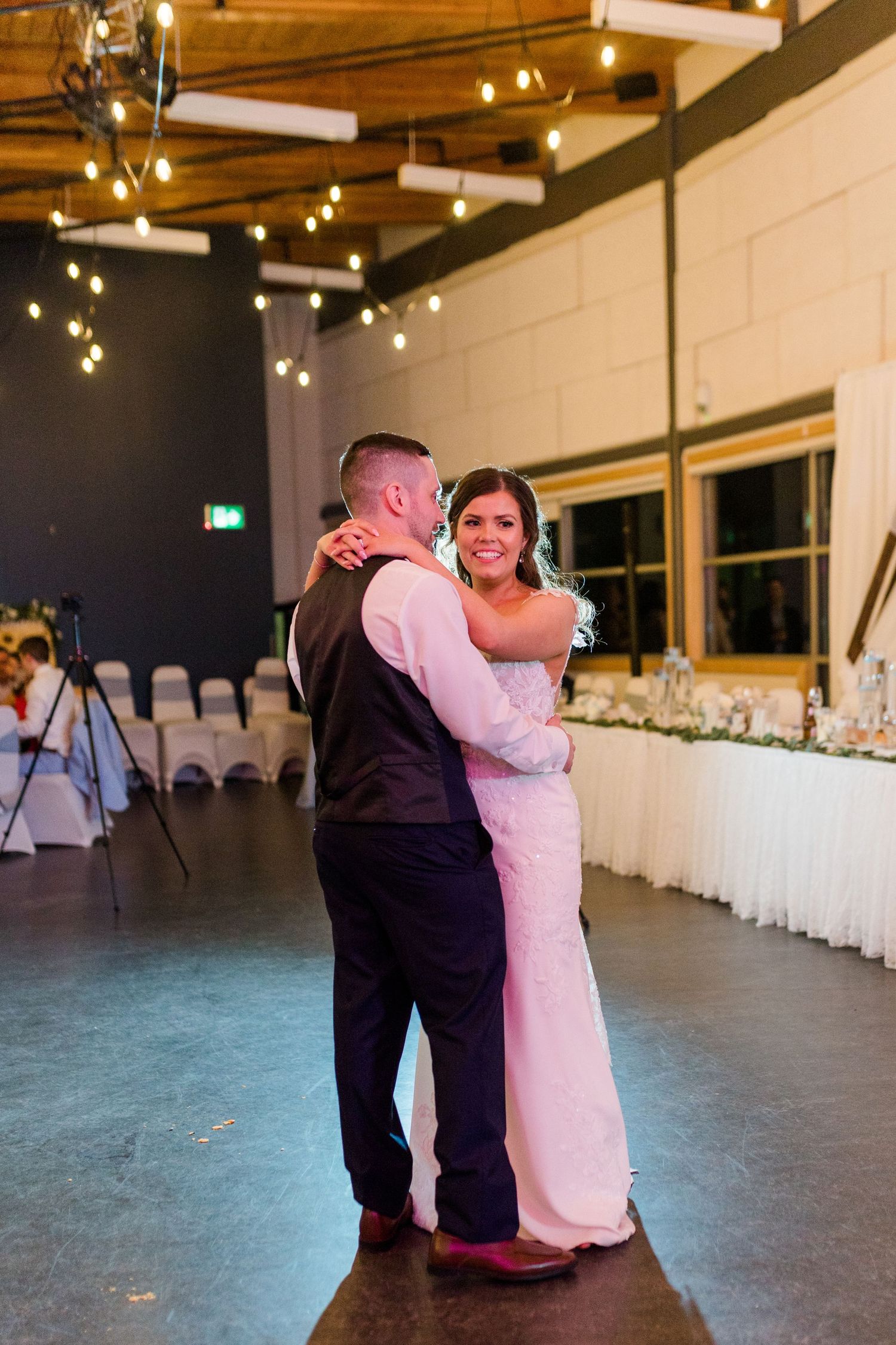 Couple dances together during their first dance at a wedding reception with spotlights and decorative lighting.