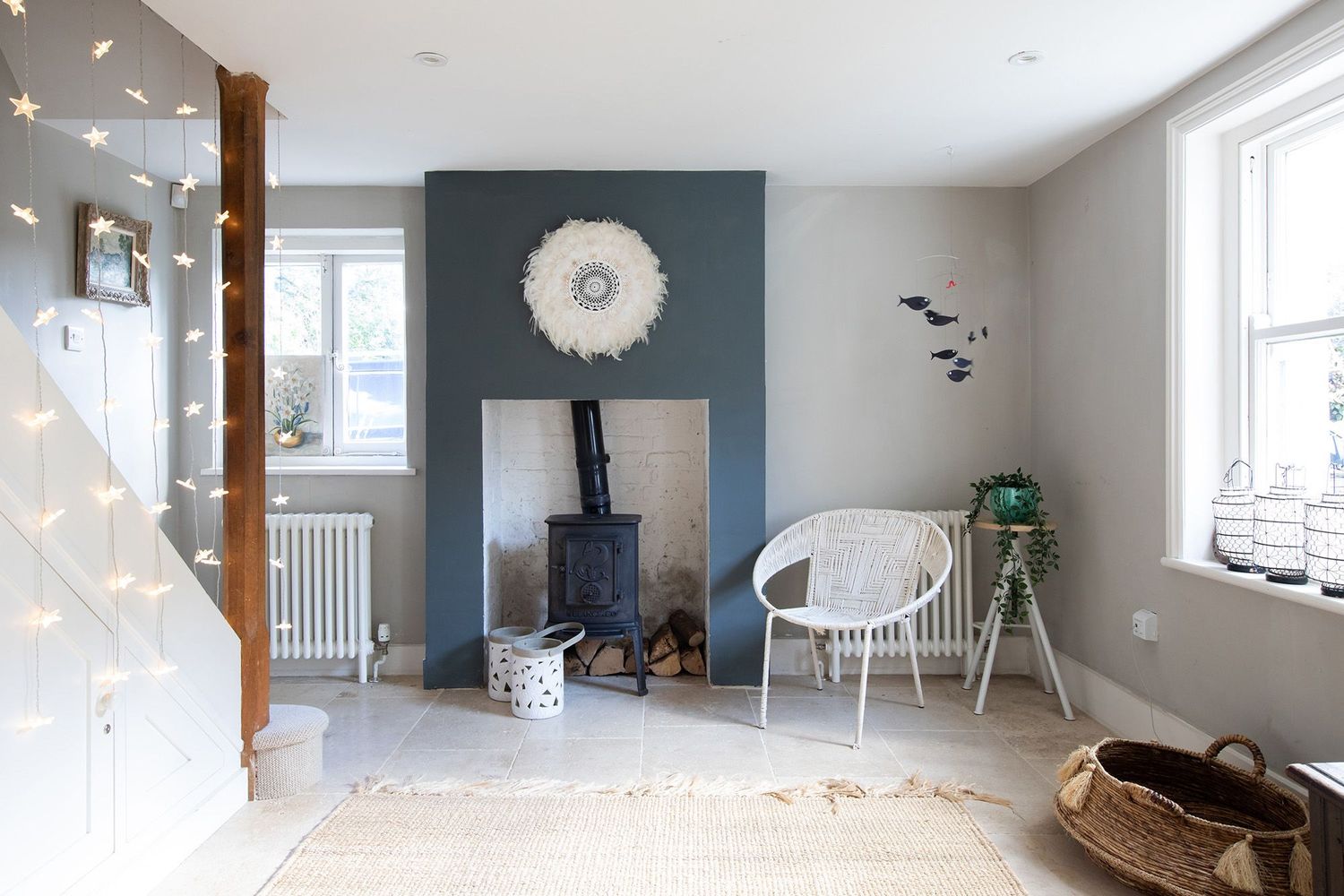 Cozy living room with wood burning stove, woven chair and decorative wall art.