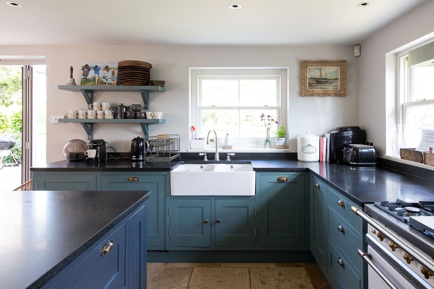 Country kitchen with blue cabinets, farmhouse sink and black countertops.