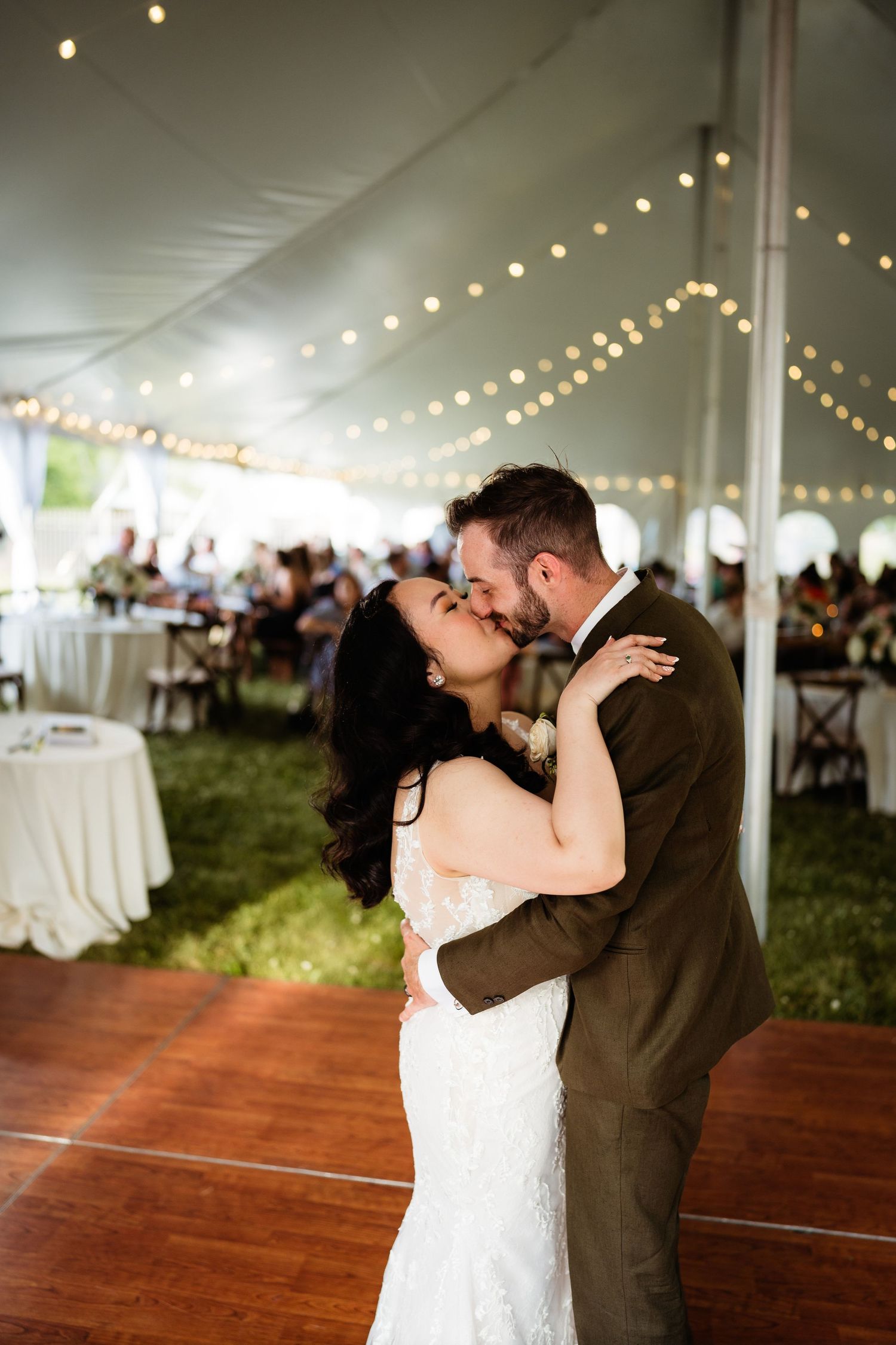 A romantic dance between newlyweds on a wooden dance floor under twinkling lights.