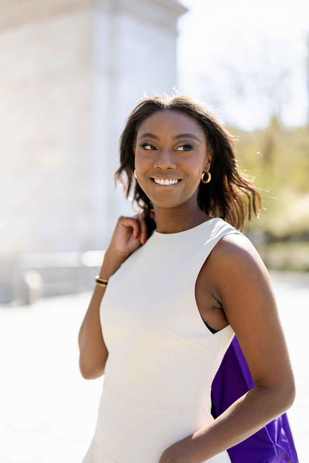 Radiant graduation portrait with white dress against classic architecture.