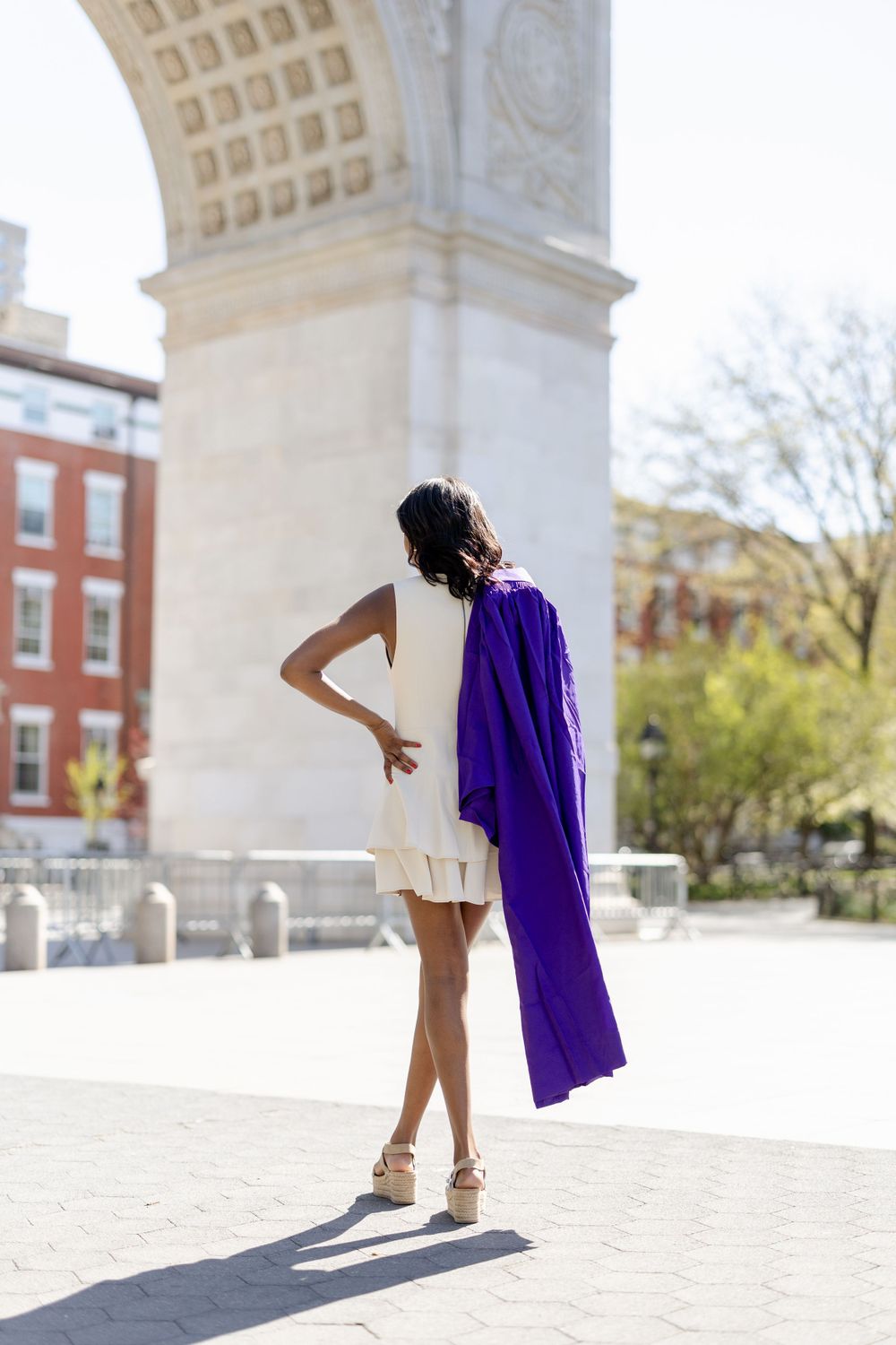 Artistic graduation pose showing purple gown movement under historic archway.