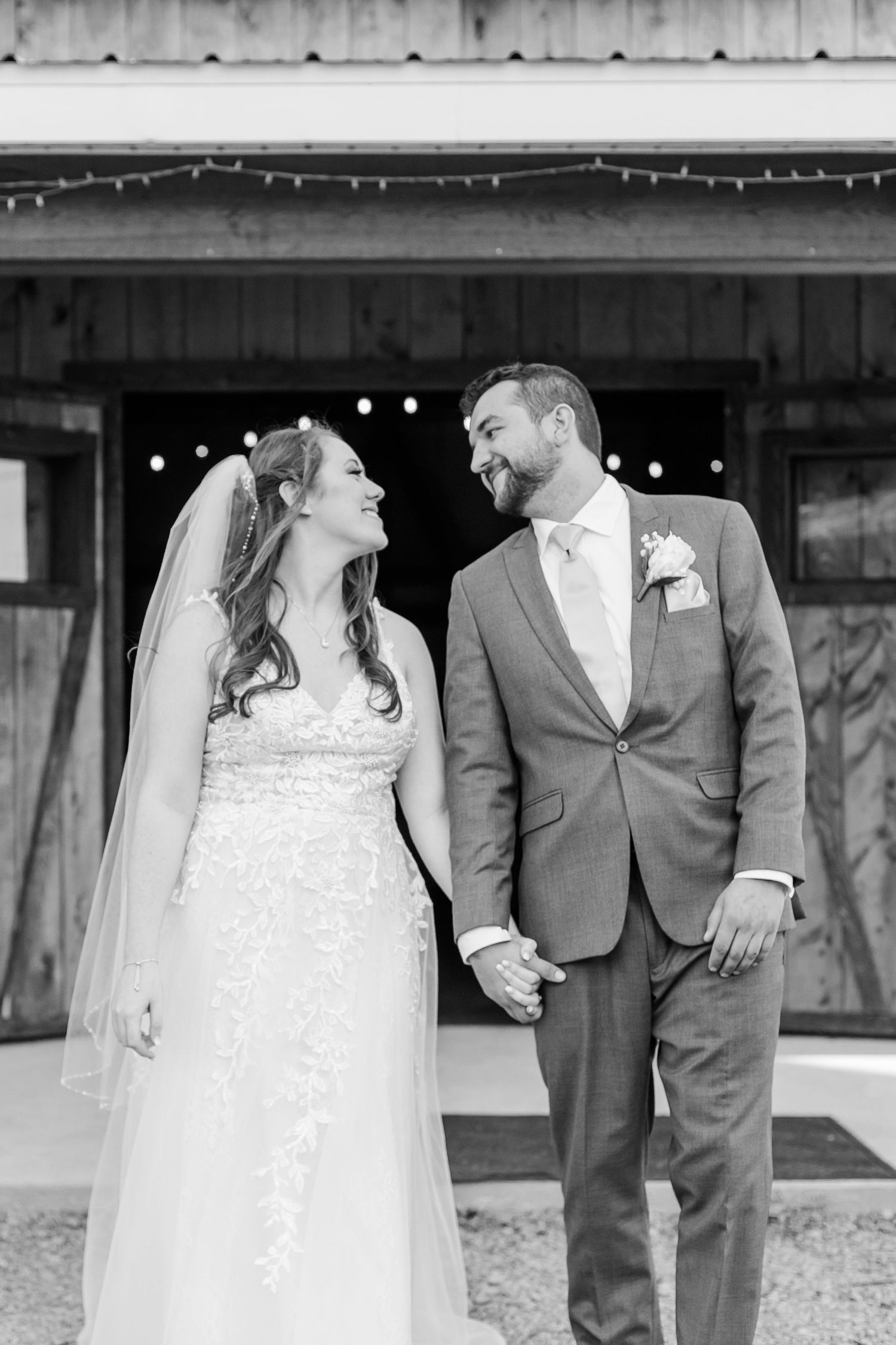 Black and white wedding portraits showing couple in formal attire under string lights.