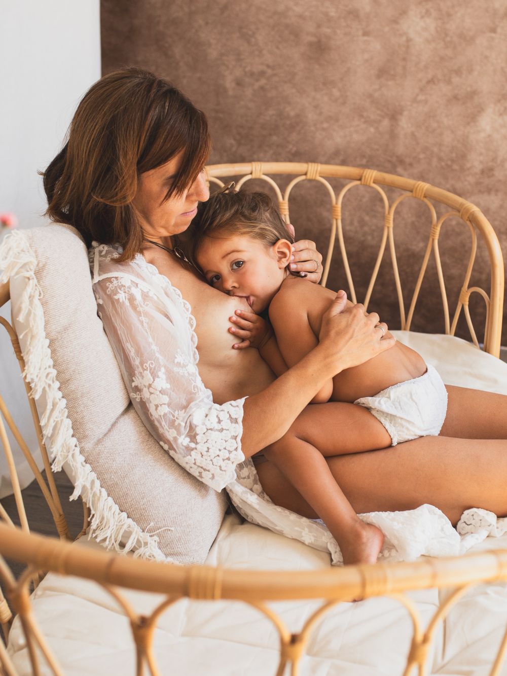 Intimate bonding moment captured on wicker chair with white lace details.