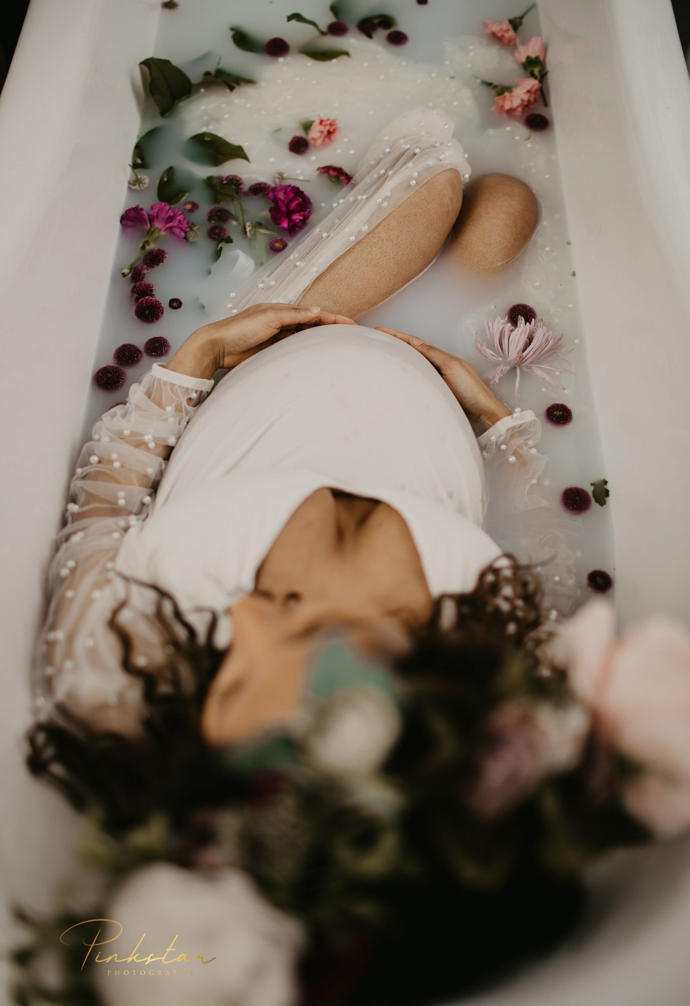 Artistic milk bath photography with flowers floating in white water.