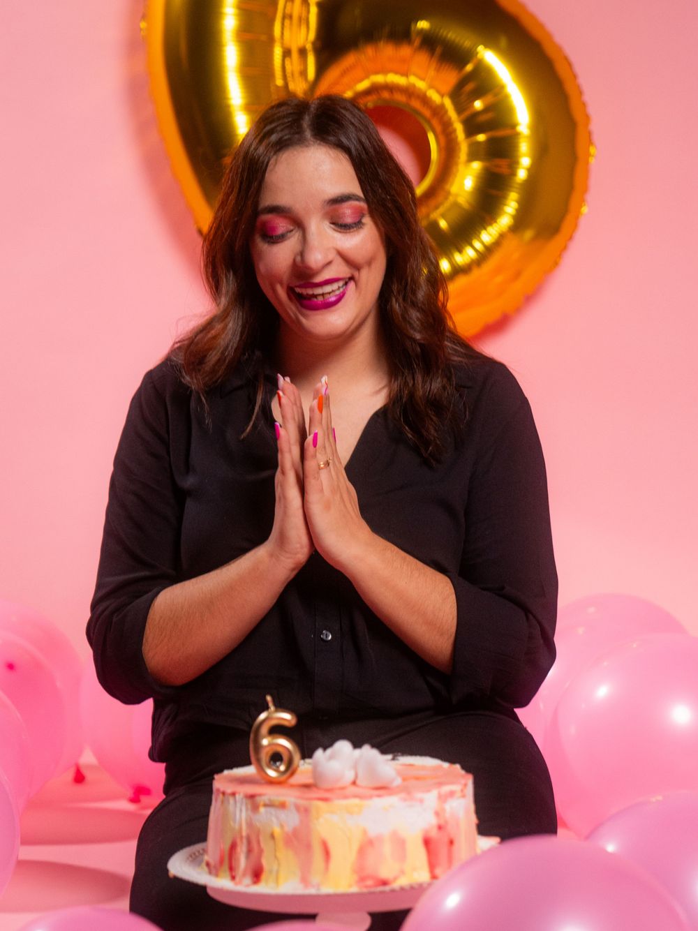 Joyful birthday celebration scene with cake and gold number balloon decoration.