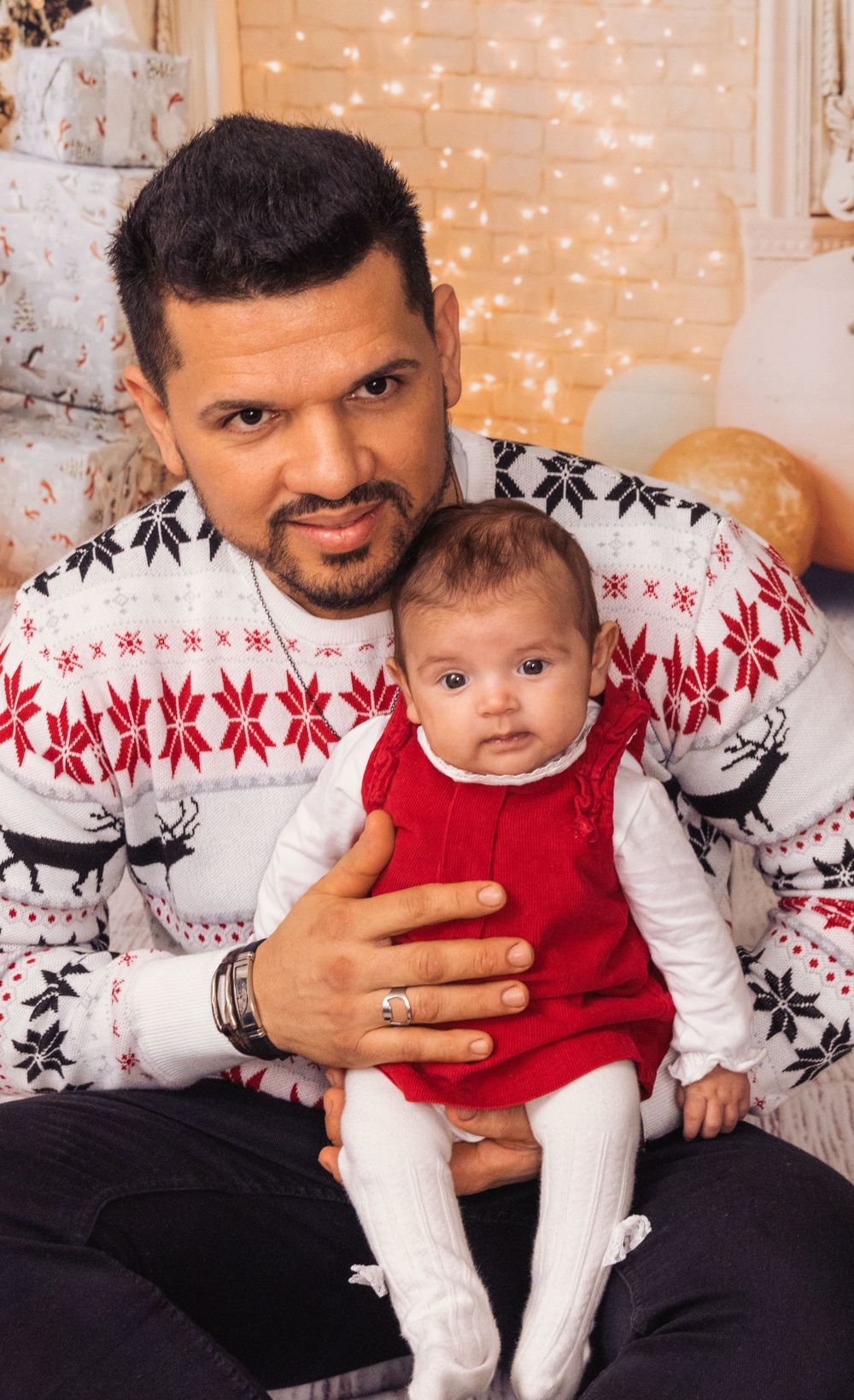 Holiday portrait featuring matching reindeer sweaters and Christmas decorations.