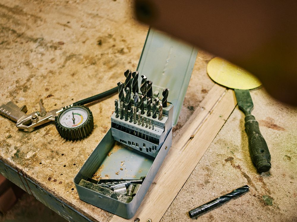 Vintage drill bits and measurement tools on worn wooden workbench.