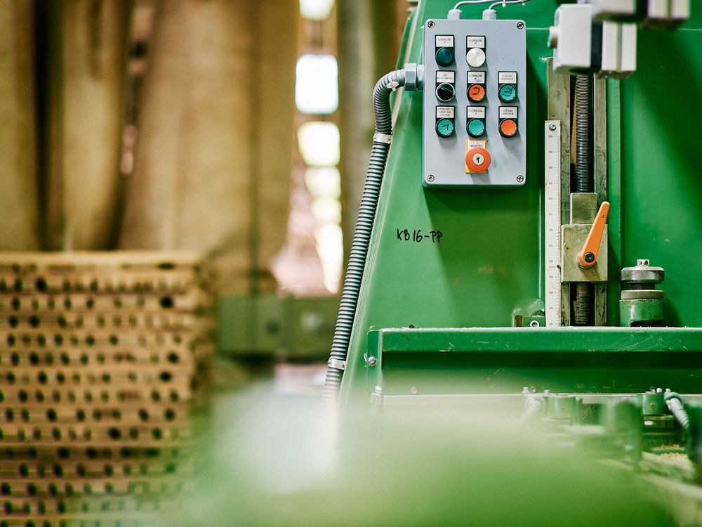 Industrial control panel with buttons mounted on green machinery in a factory setting.