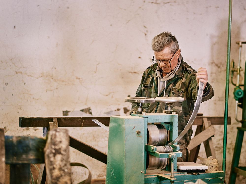 Worker operating industrial machinery in manufacturing workshop.