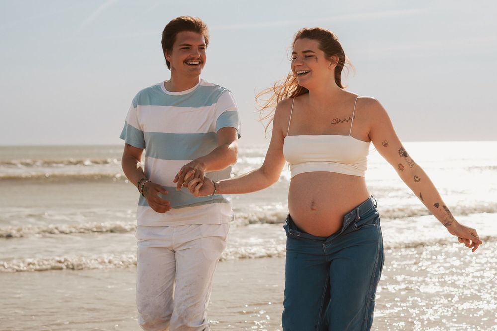 Happy couple walking and laughing together along beach shoreline.