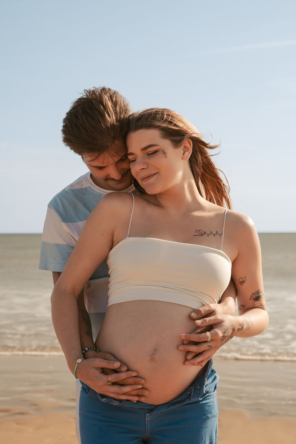Expectant couple sharing tender moment during beach maternity session.