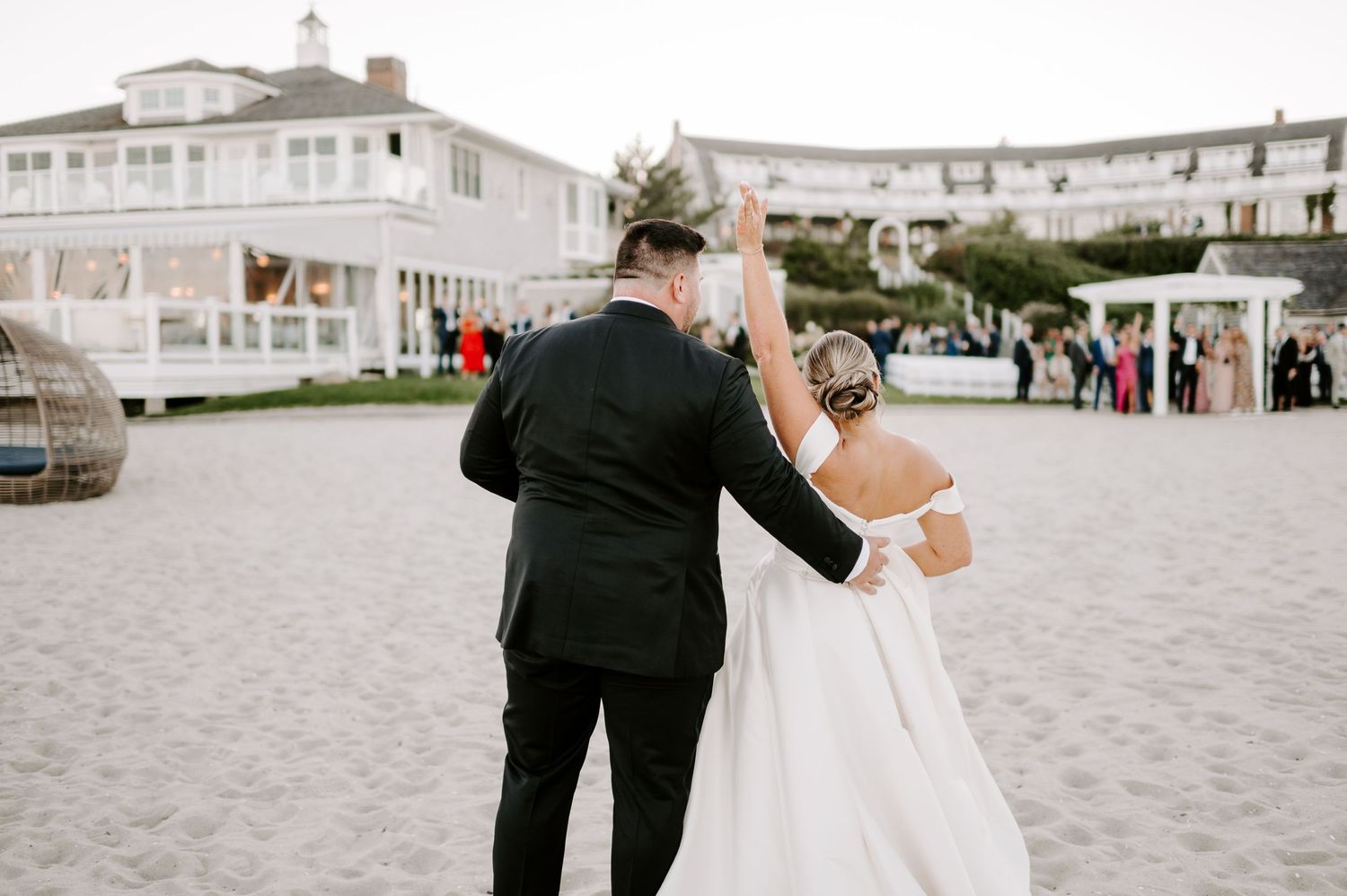 Wedding couple shares romantic moments on a beachfront with buildings visible in the background.