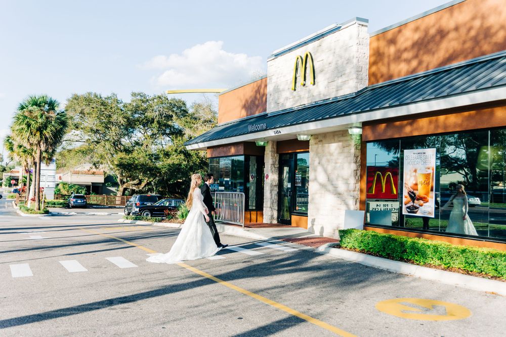 Wedding couple in formal attire outside McDonald's restaurant.