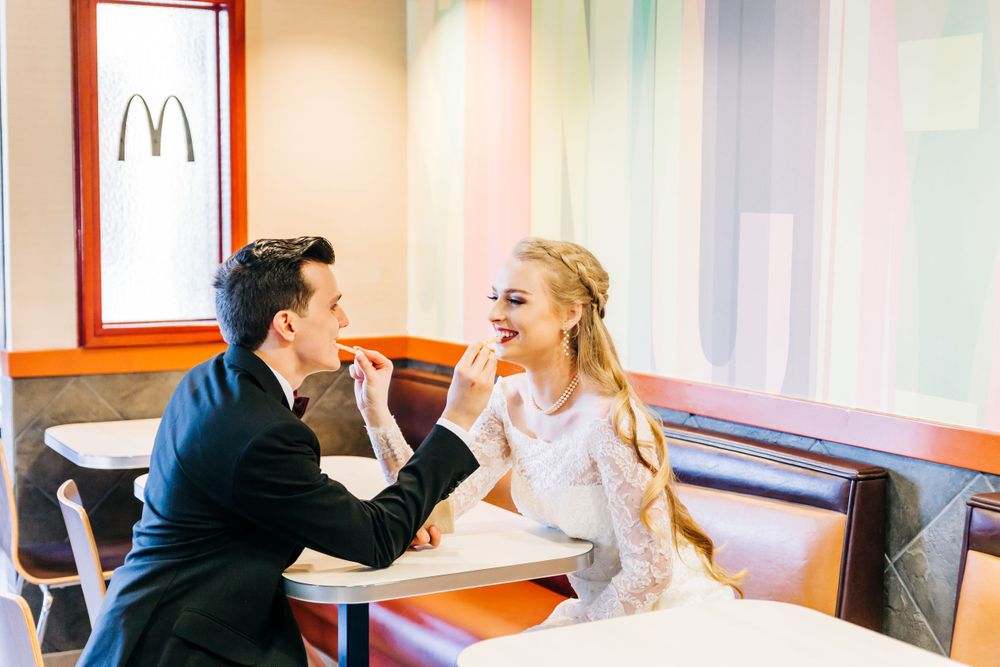 Newlyweds feeding each other french fries at McDonald's restaurant.
