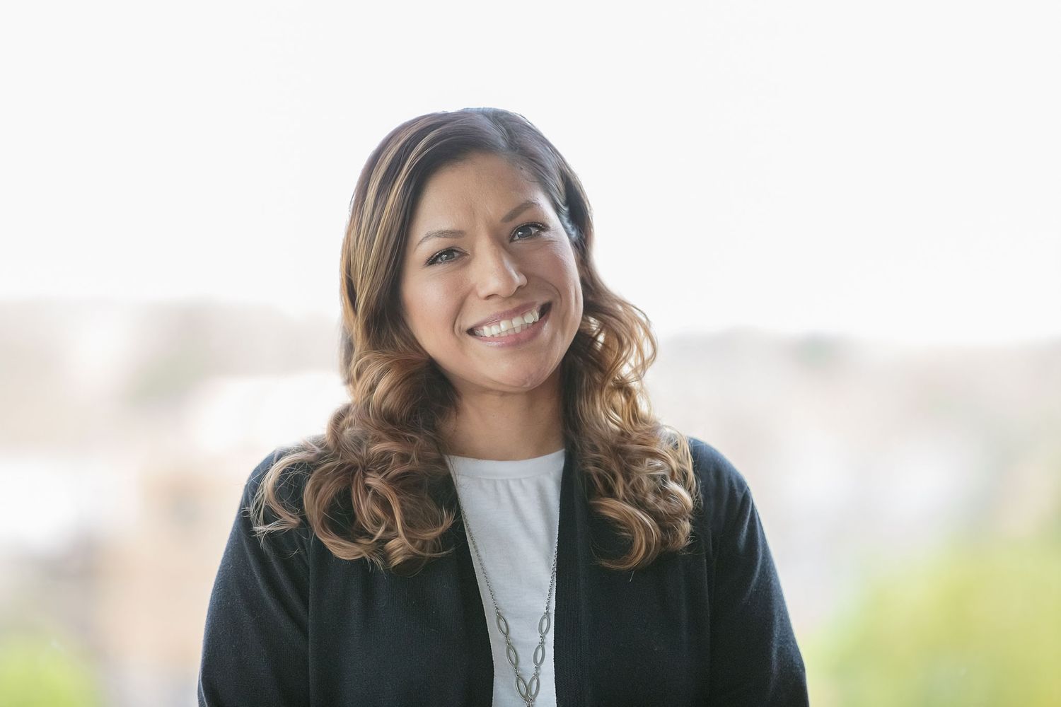 Headshot photo of a beautiful spanish woman with a bright backlit background
