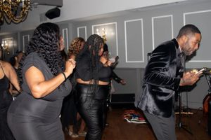 People dancing and enjoying themselves at an indoor event with gray paneled walls.