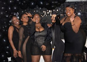 Group of friends posing together against a sparkling backdrop at a nighttime celebration.