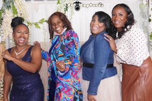 Four friends strike playful poses against a floral backdrop at a special event.