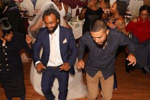 Two people dance energetically on a wooden dance floor at a celebration.