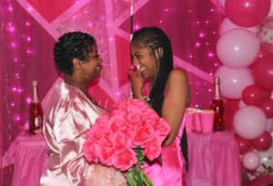 Two people sharing a romantic moment with pink roses at a decorated Valentine's themed celebration.