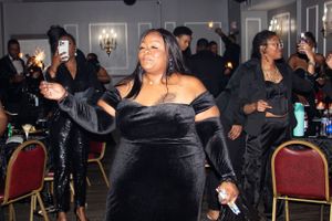 Woman in black velvet dress dancing at an elegant indoor party venue.