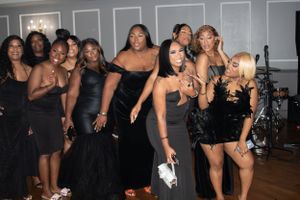 Party guests in coordinated black attire dance and celebrate in an indoor venue.