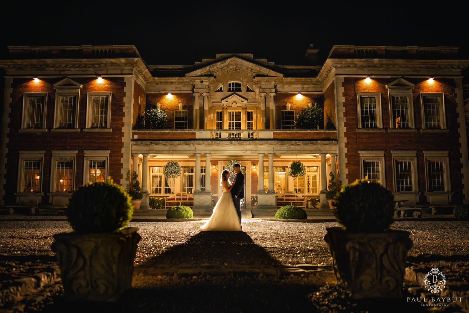 Elegant historic mansion illuminated at night with grand architecture and landscaping creates a romantic wedding scene.