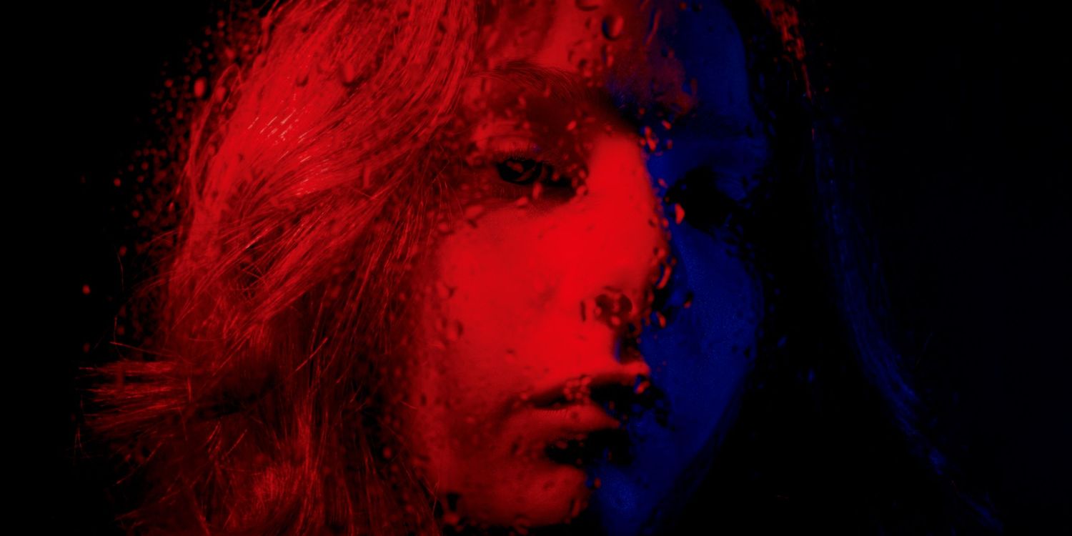 girl looks through rainy window at coloured lights