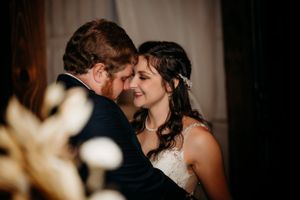 Bride and groom share a tender forehead-to-forehead moment in soft romantic wedding portrait.