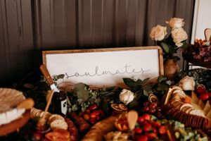 Elegant wedding charcuterie board with soulmates sign, roses, and assorted foods.