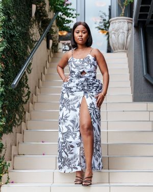 White and navy floral maxi dress with slit posed on beige stone staircase.