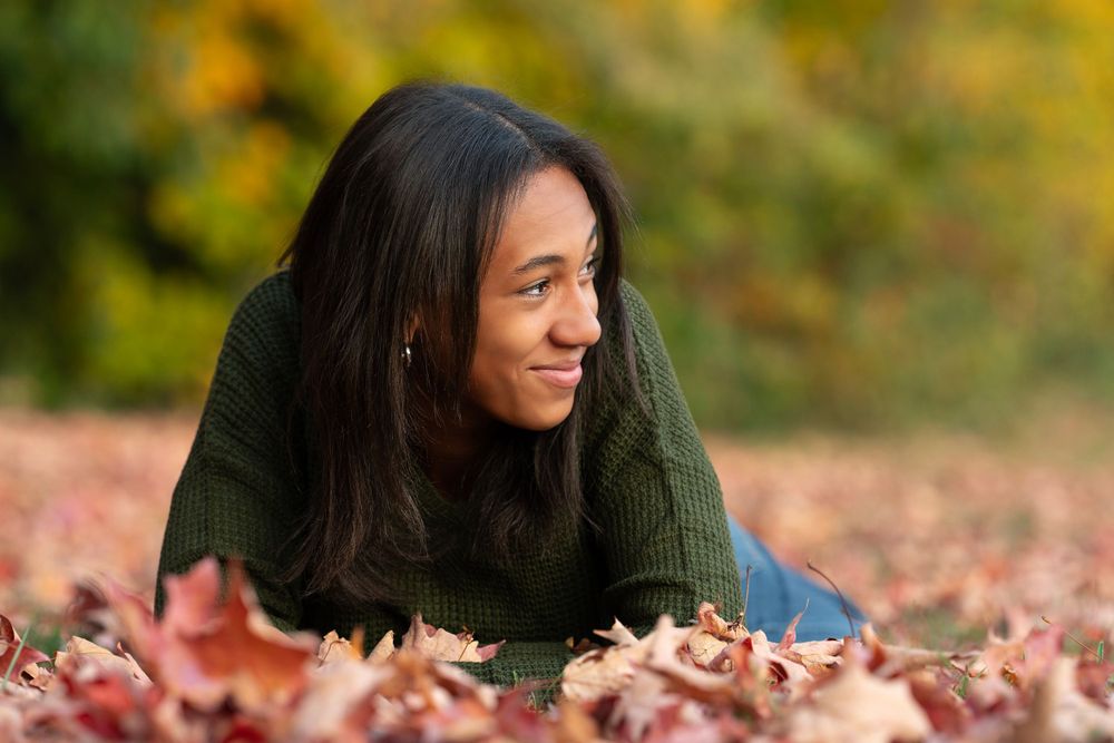 teen girl smiles in fall leaves