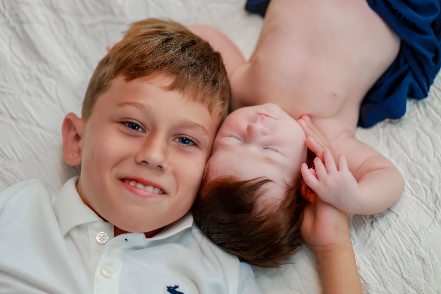 A big brother snuggles his new baby sibling for an adorable picture