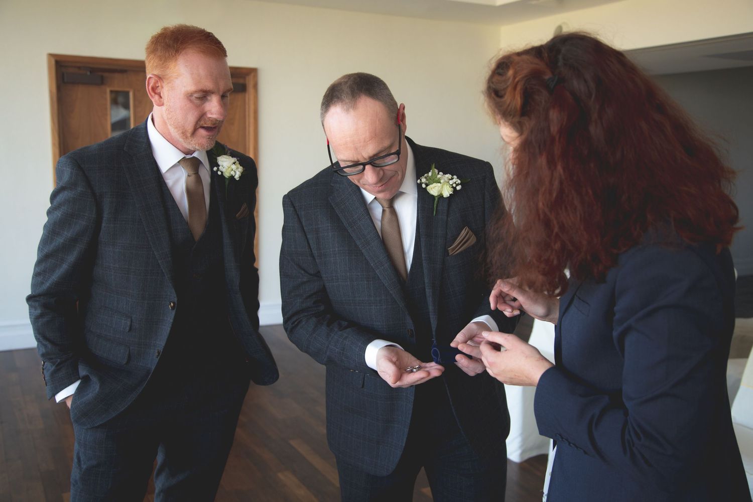 Three people in formal attire examining something on a mobile device.