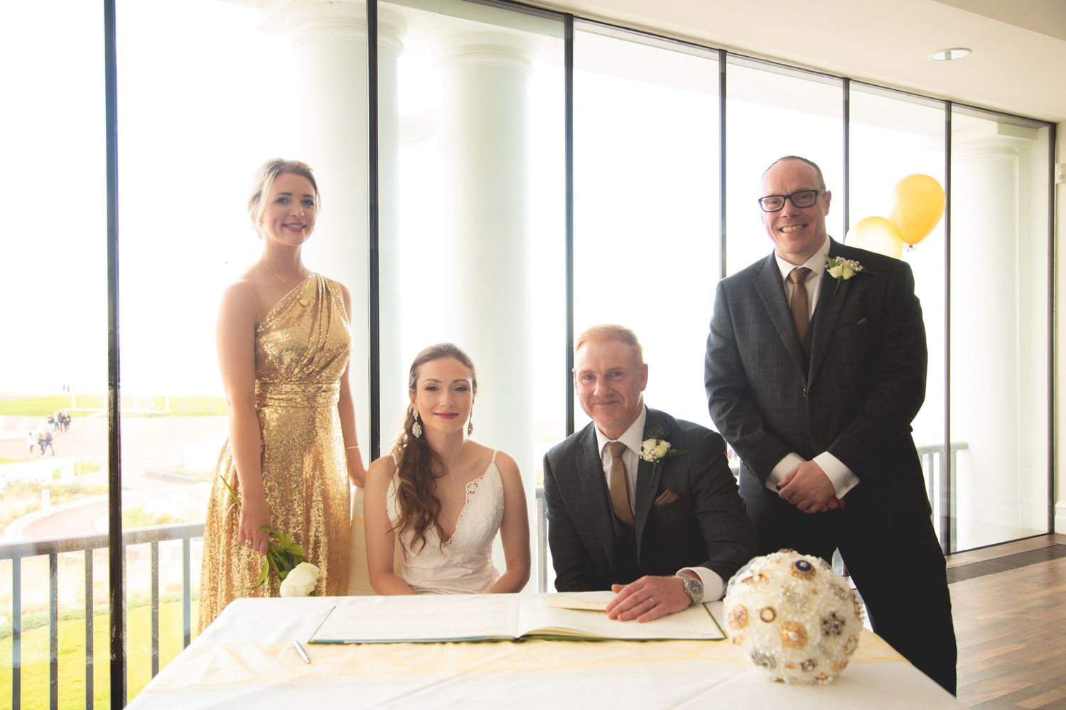 Wedding signing ceremony at bright venue with ornate bouquet on registration table.