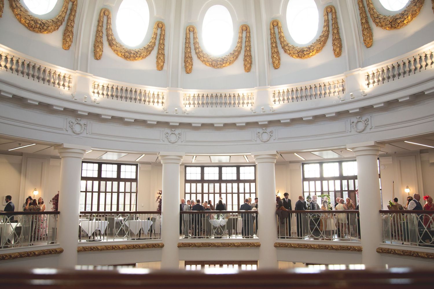 Elegant white rotunda interior with circular balcony and ornate crown molding illuminated by natural light.