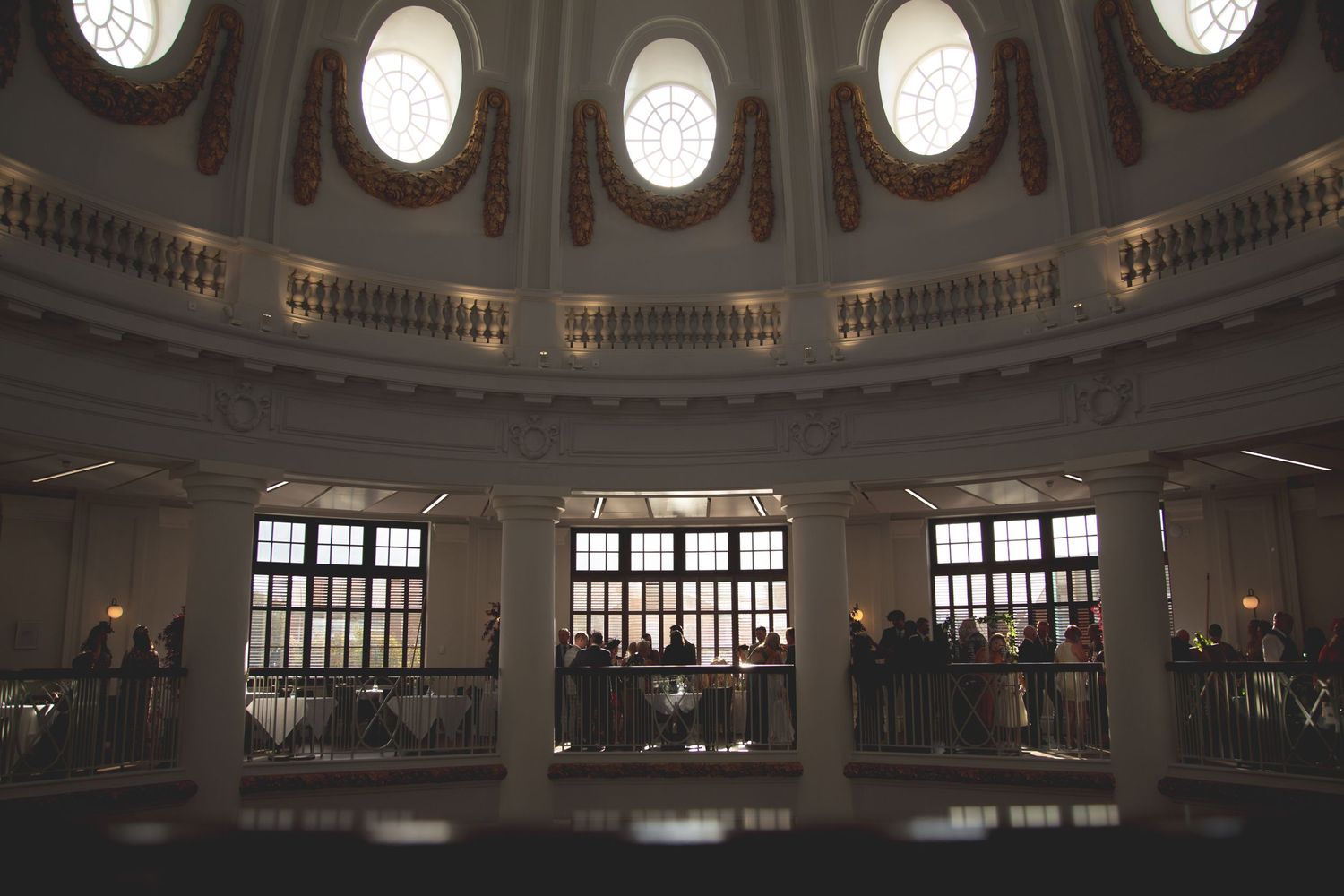 Dramatic view of circular balcony inside historic domed building with natural light streaming through windows.