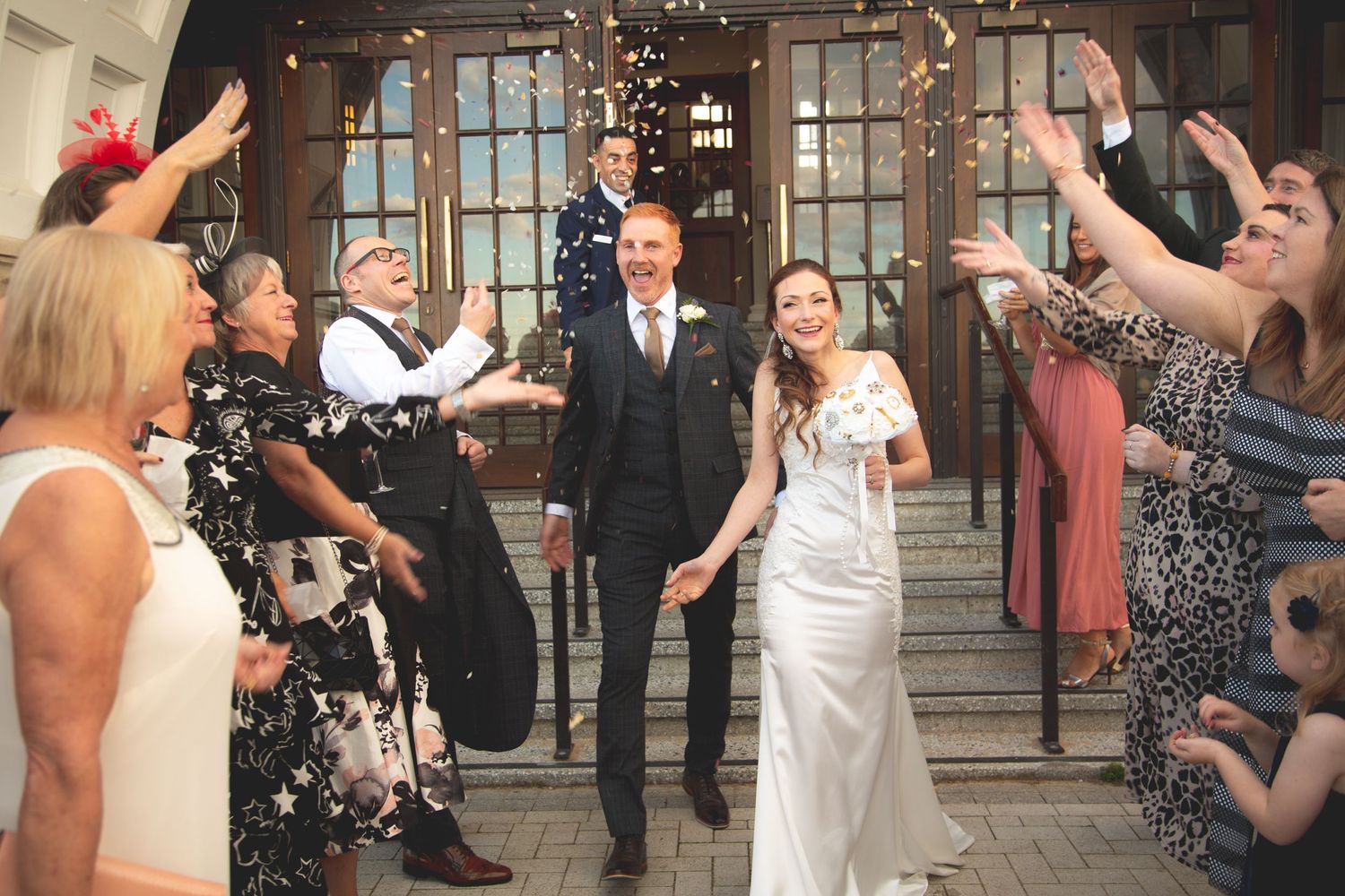 Guests shower newlyweds with confetti as they exit historic building entrance.