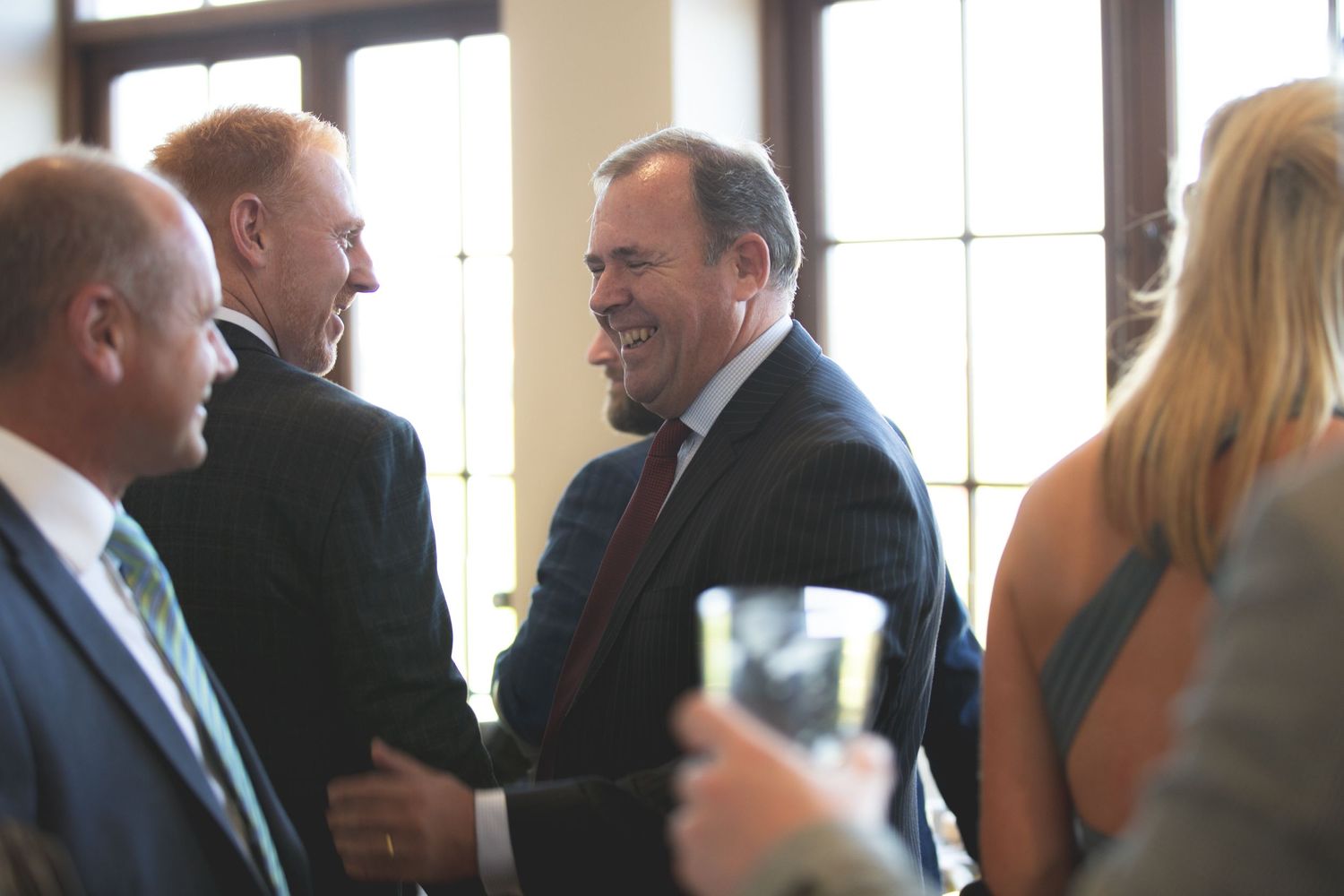 Guests in formal attire socializing with drinks at an indoor event.