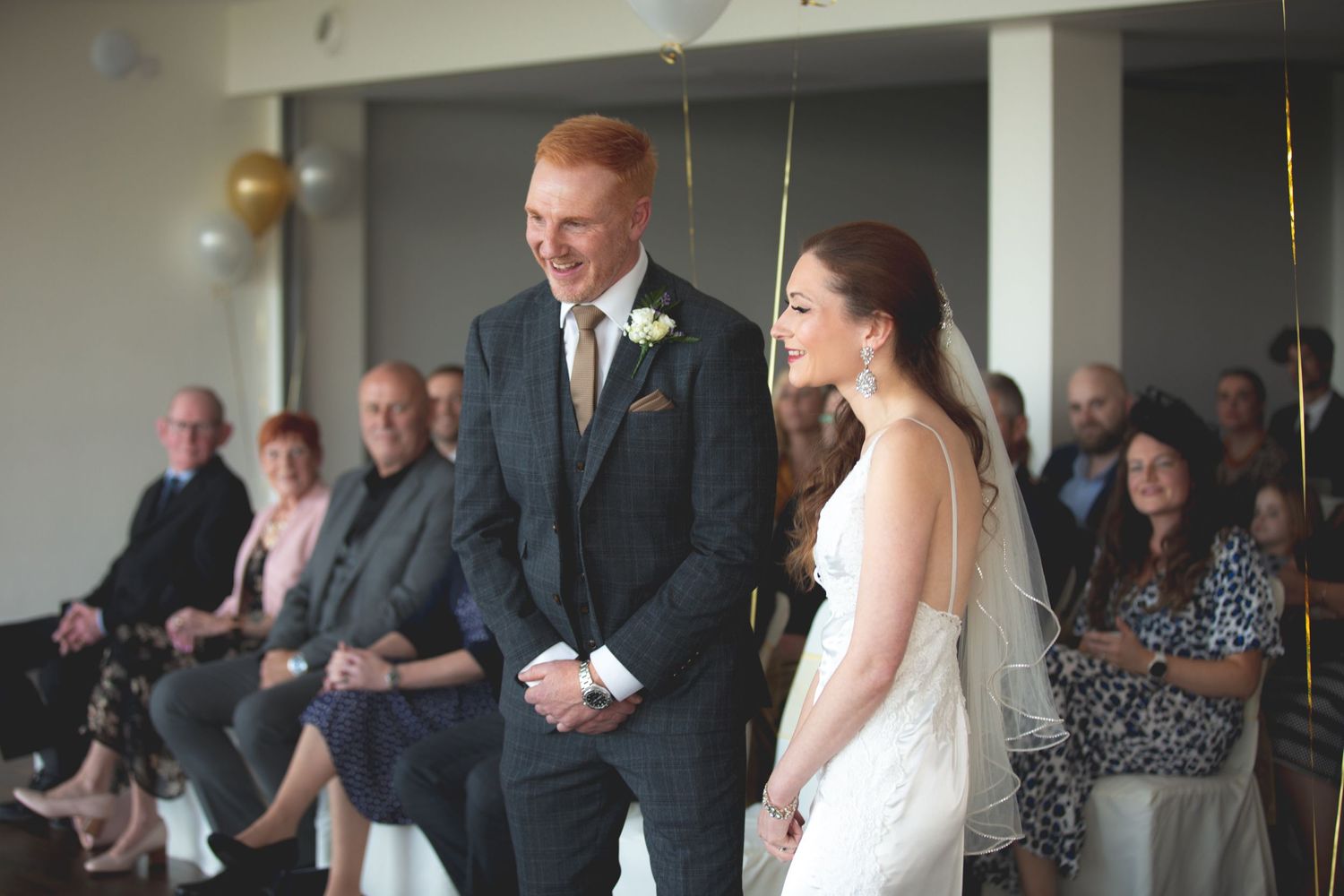 A bride and groom stand together during their wedding ceremony as guests look on.