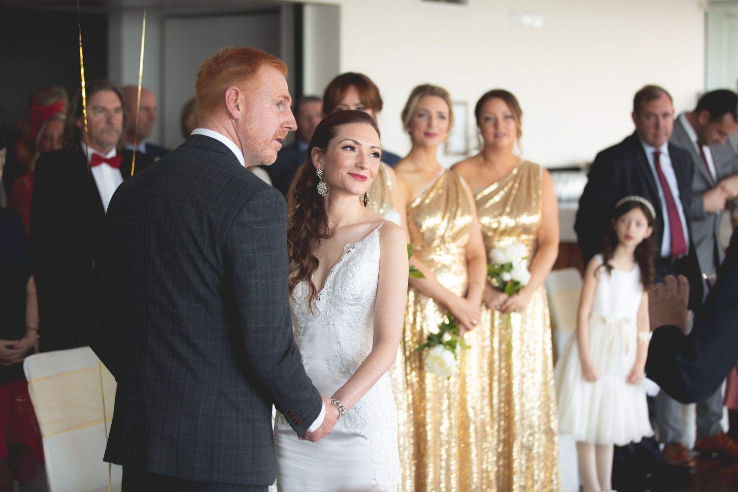 A wedding ceremony with attendants in metallic gold dresses standing beside the couple.