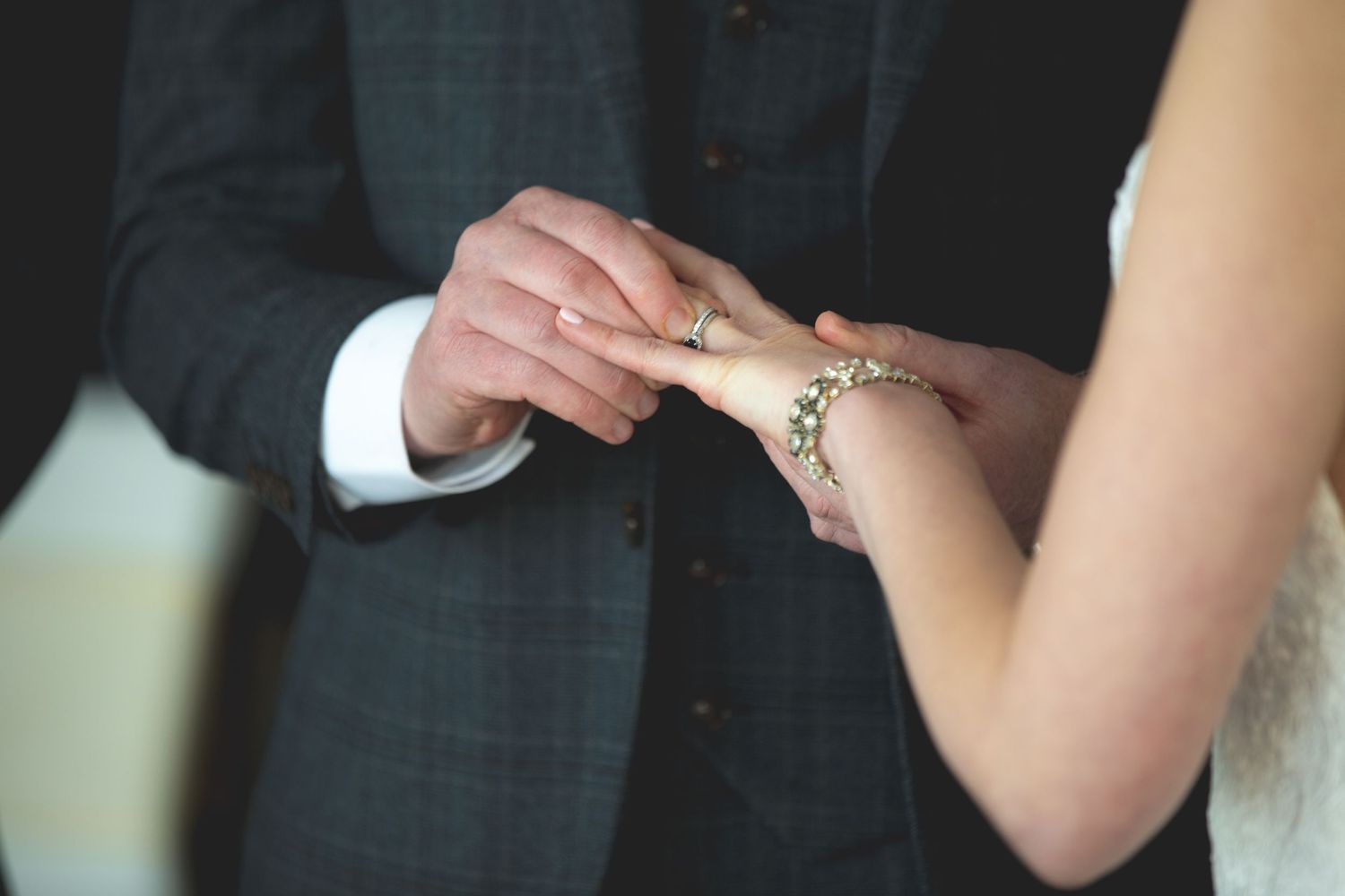 Close-up of hands exchanging wedding rings during a ceremony.