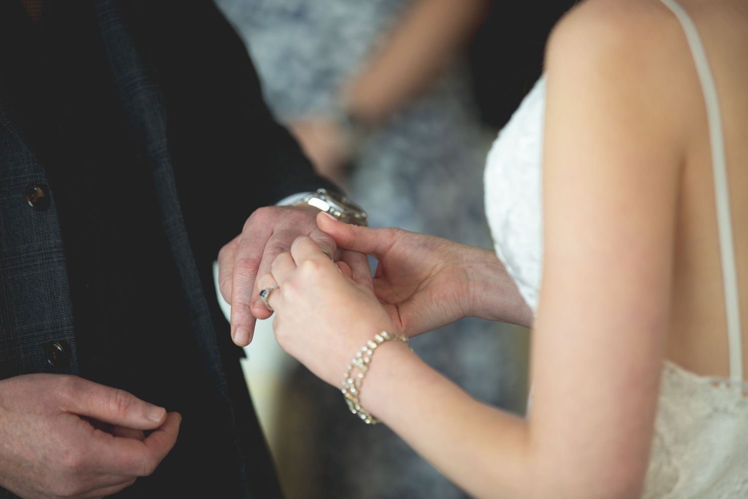 Detailed shot of hands exchanging rings during wedding ceremony.