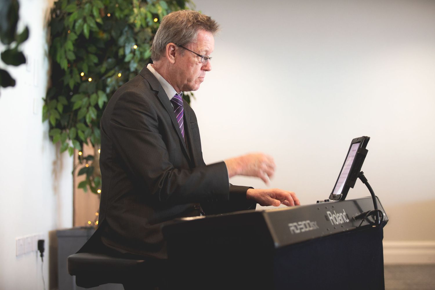 Musician playing keyboard during indoor wedding ceremony.