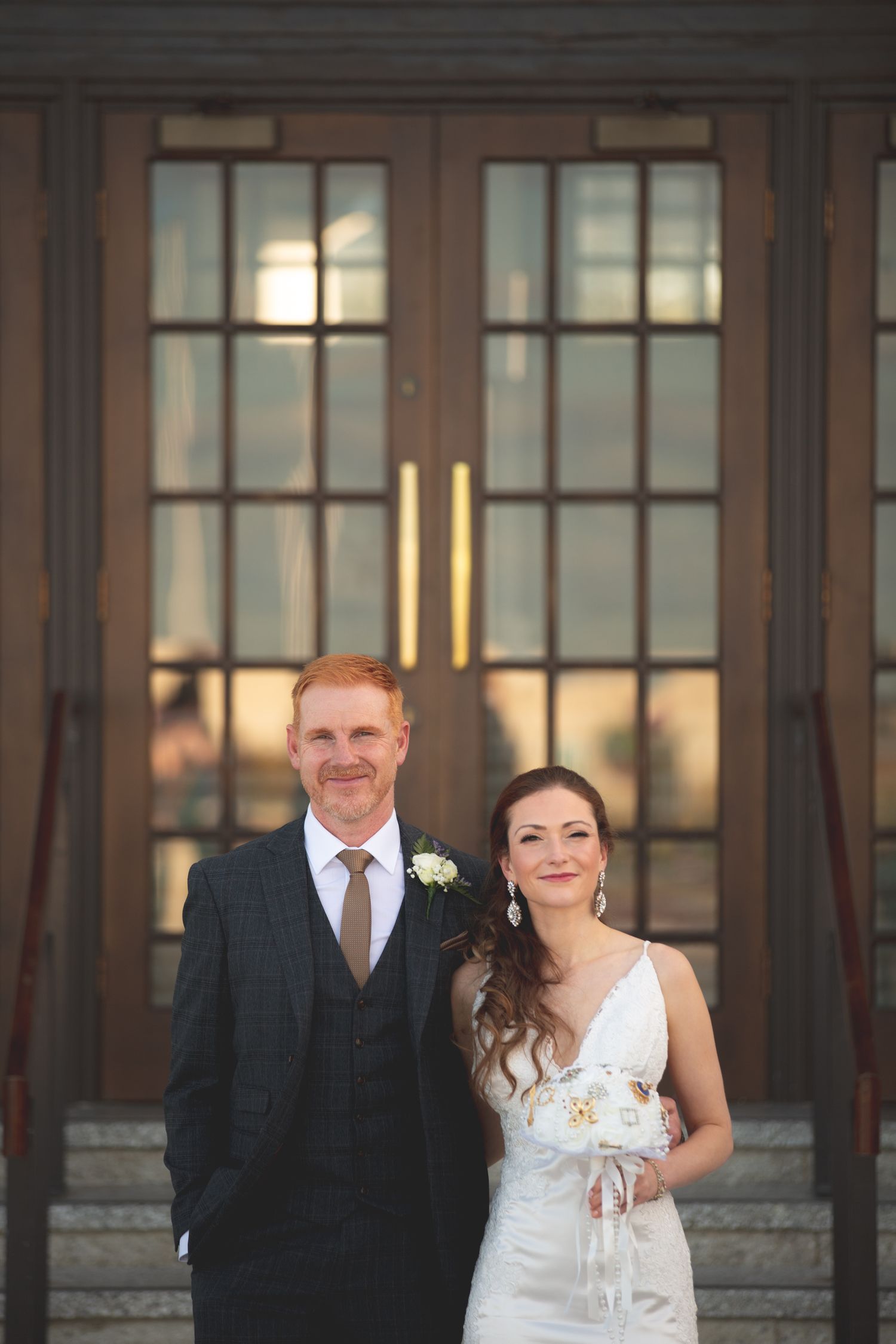 Newlyweds share intimate moment outside historic building during sunset.